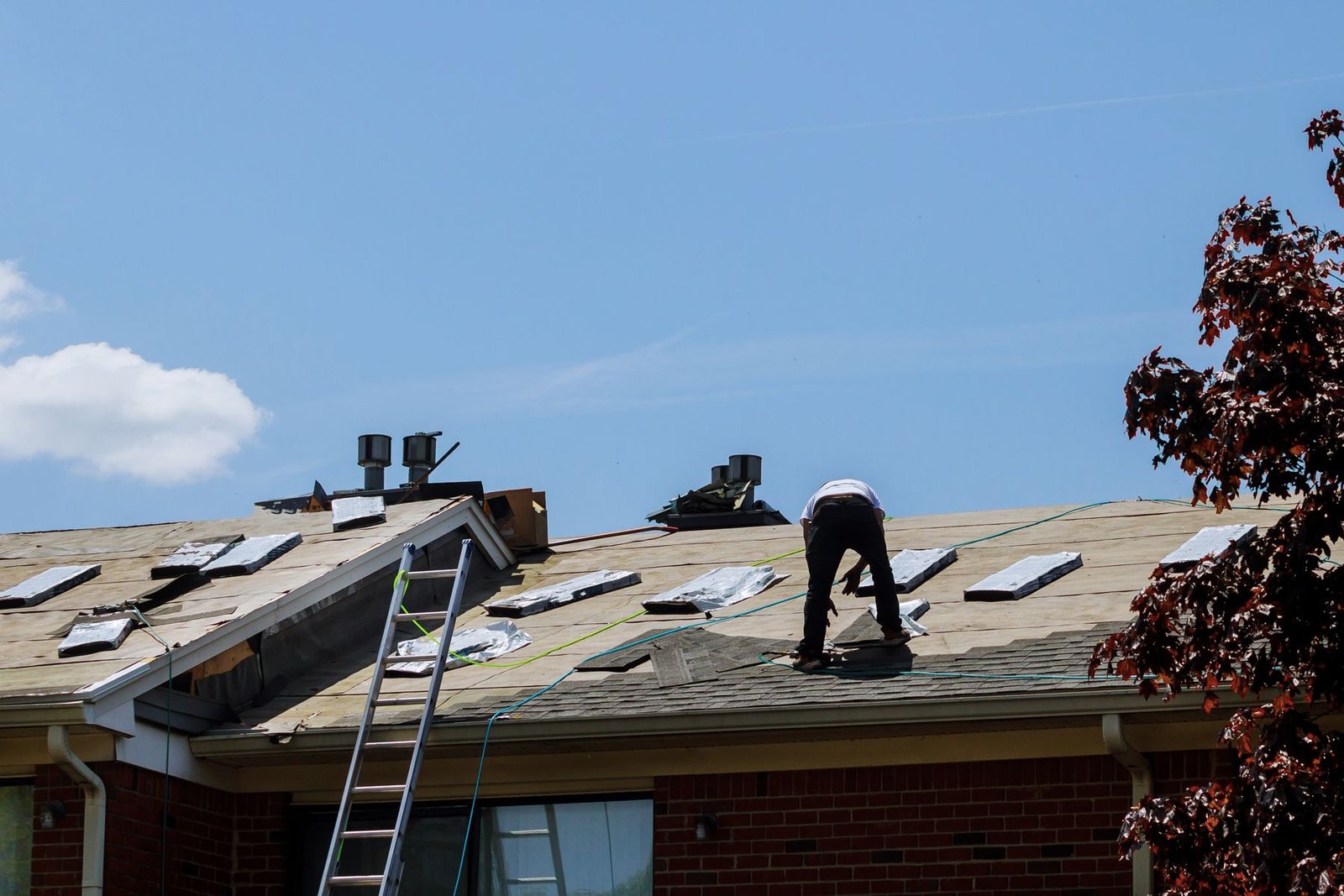 A roofer on the roof of a brick Louisville home, near the chimney line